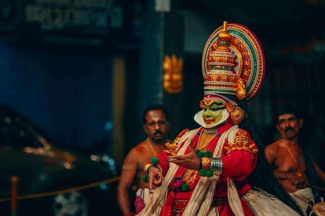 Kathakali tiyatrosunda oyuncular yoğun makyaj ve renkli kostümlerle sahne alıyor.
