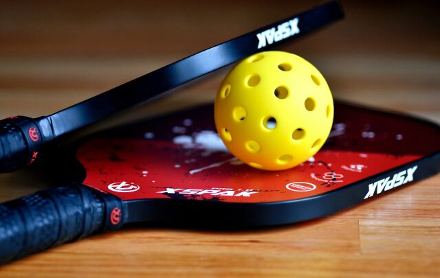 Pickleball küreğe benzeyen bir raket ve delikli plastik bir topla oynanıyor. 