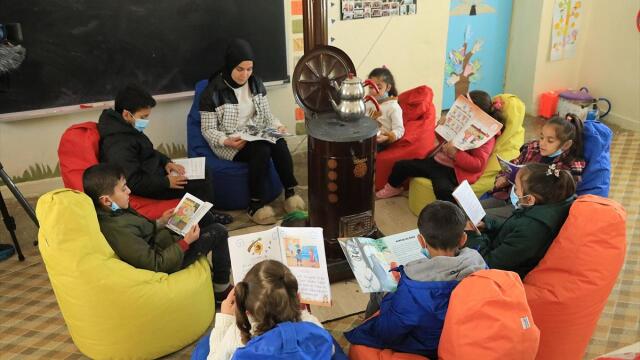 Emine Yılmaz, öğrencileriyle birlikte kitap okuyor ve ukulele öğretiyor. 